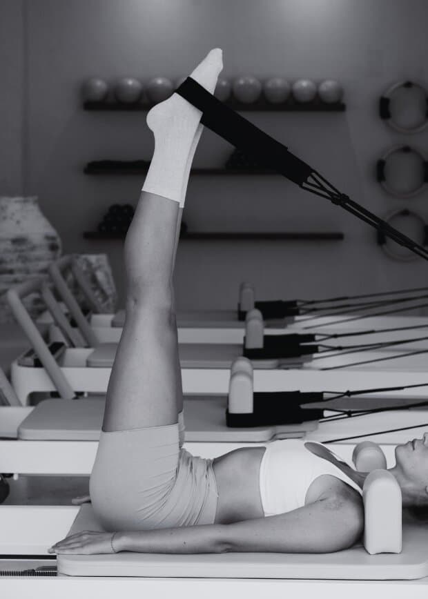 Pilates reformer in a bright studio with legs extended in a controlled exercise